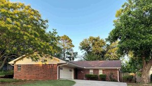 A single-story brick house with a garage, a front yard, and mature trees. - Game Day Getaway 2 – Easy Walk to OSU Stadium (Stillwater)