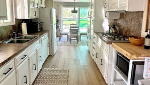 A spacious kitchen with white cabinets, a wooden countertop, and a view to a patio. - 
Your Borrego Bungalow: 2BR/2BA at Roadrunner Golf and C.C. Golf cart included! (Borrego Springs)