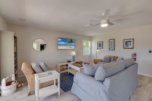 A living room with a sofa, armchair, coffee table, and a ceiling fan.