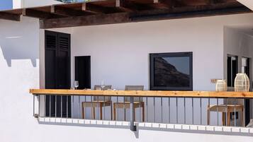 A balcony with a wooden table and chairs, a TV screen, and two doors.