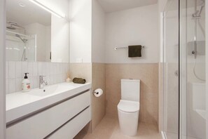 Un bagno moderno con lavandino, specchio e water bianchi.