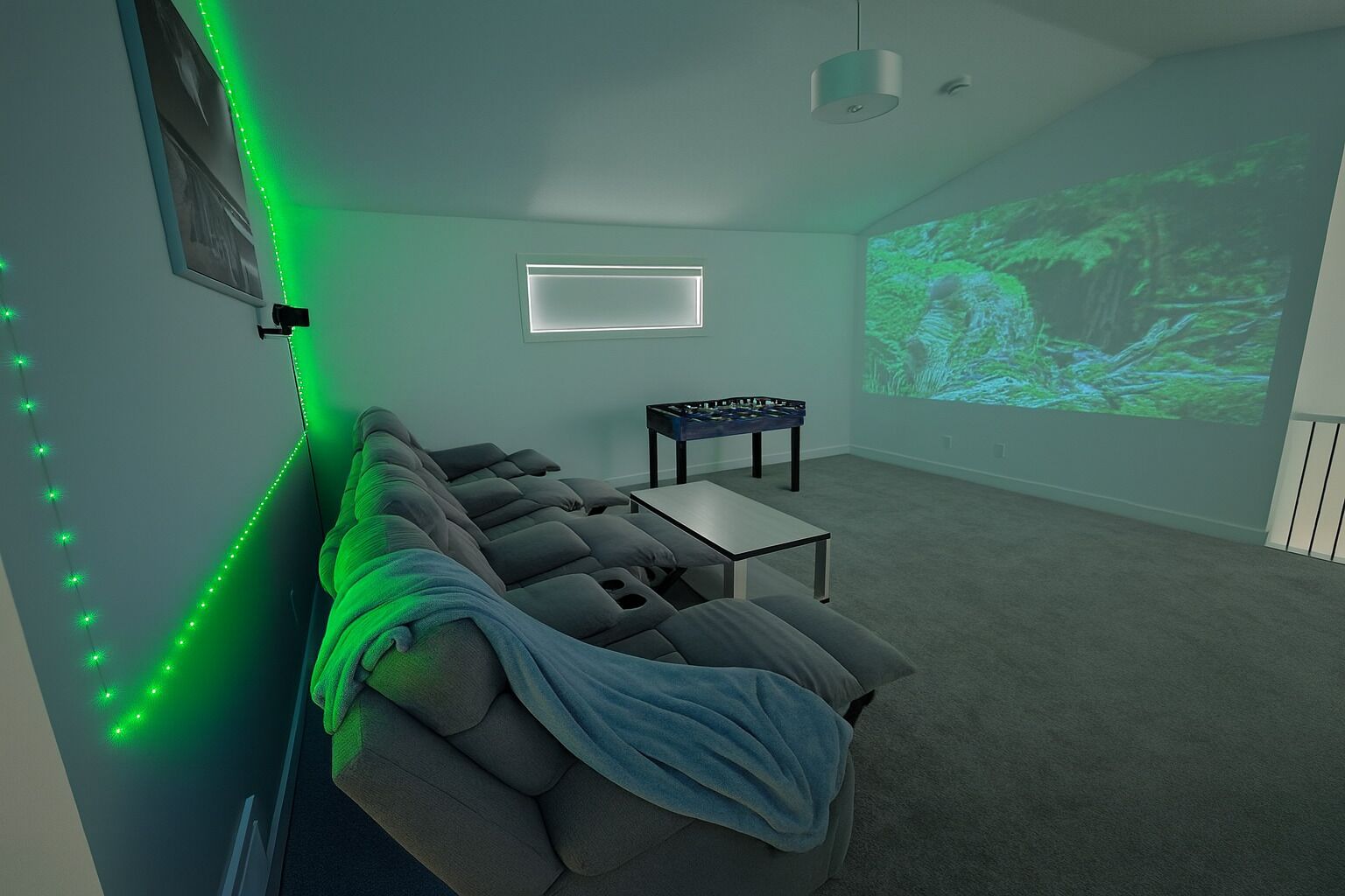 A room with a sectional sofa, a small table, and a projector screen displaying a nature scene.
