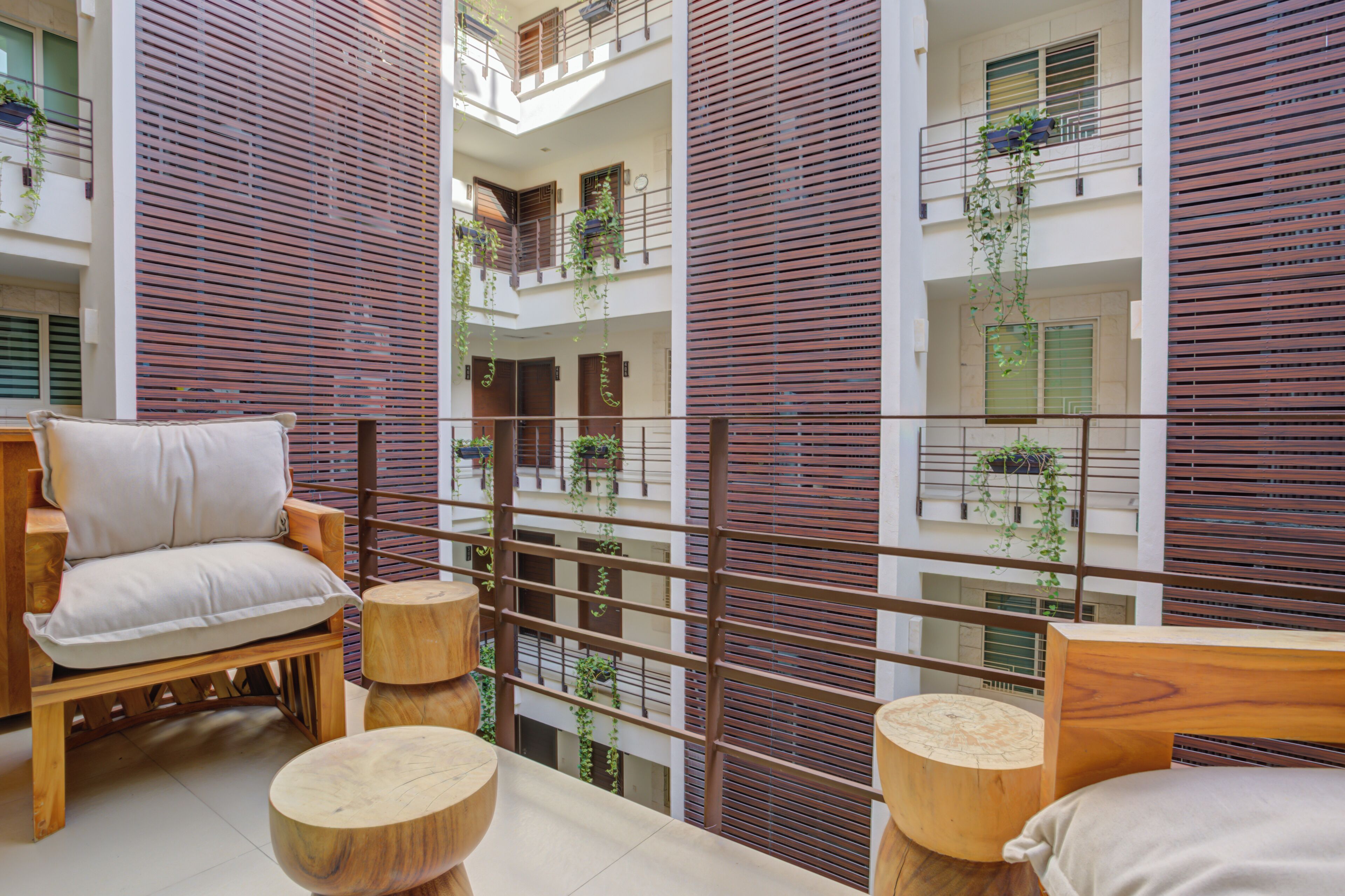 Un interior moderno con un banco de madera, mesas redondas de madera y un balcón con barandillas de madera.