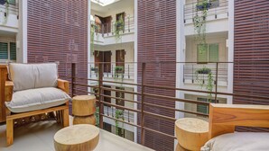 Un intérieur moderne avec un banc en bois, des tables rondes en bois et un balcon doté de balustrades en bois.