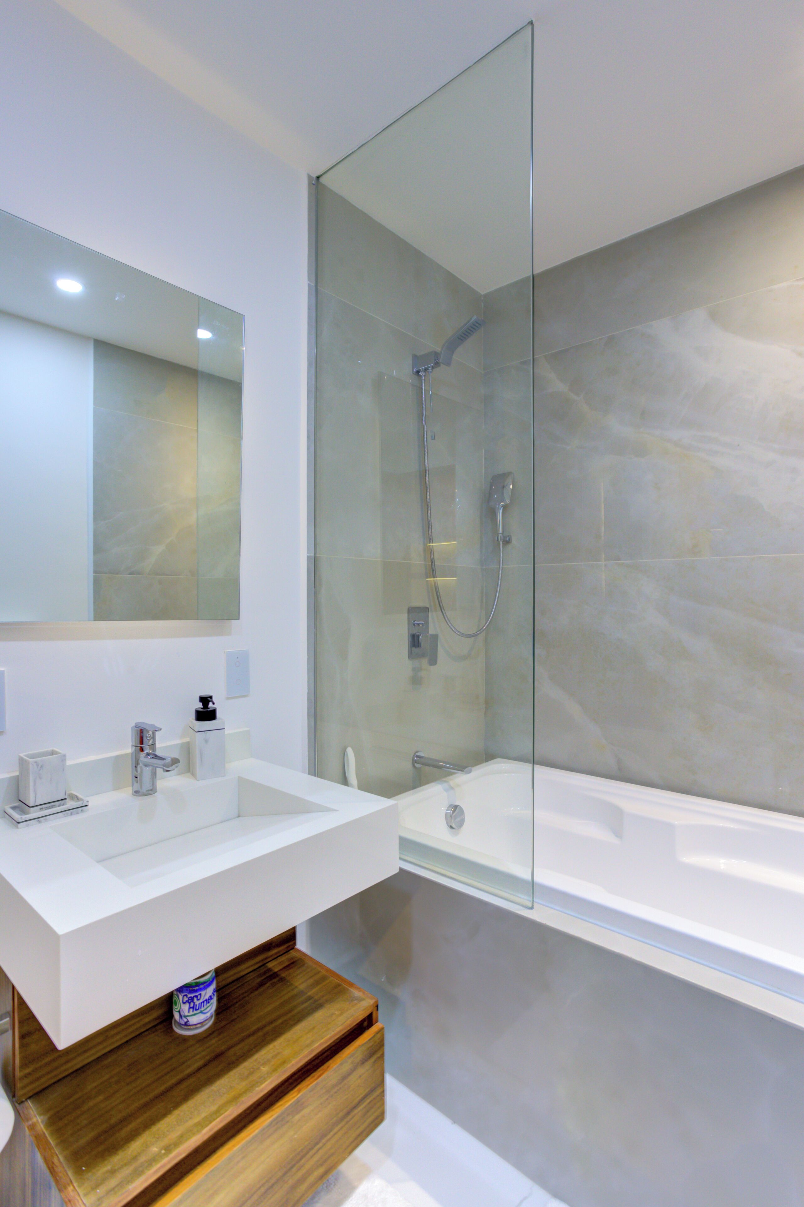Enjoy a refreshing, resort-style experience in a pristine shower and bath combo featuring a polished chrome rainfall fixture.