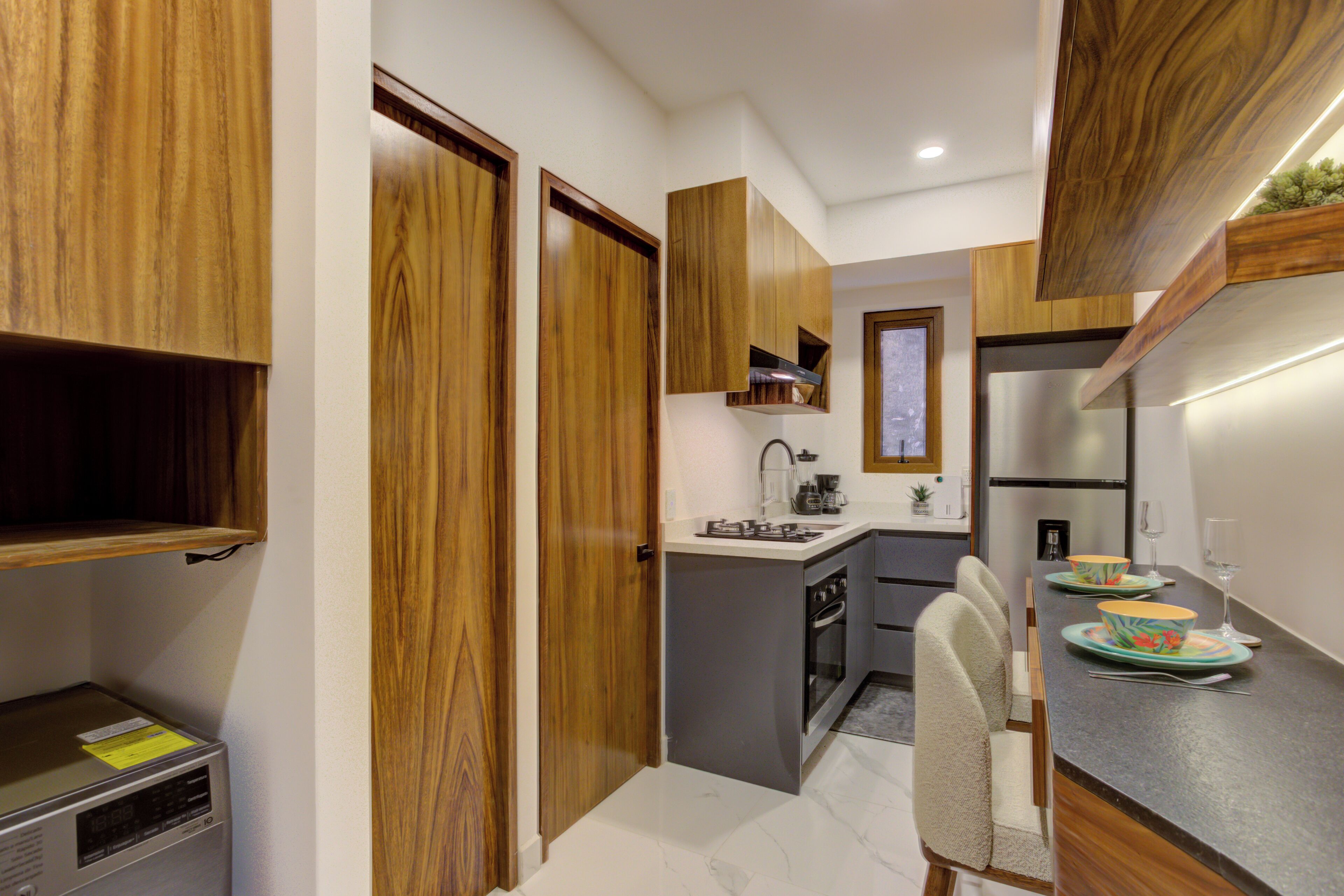 Appreciate the seamless architectural flow between the kitchen and entryway, showcasing rich natural wood doors and clean, minimalist lines.