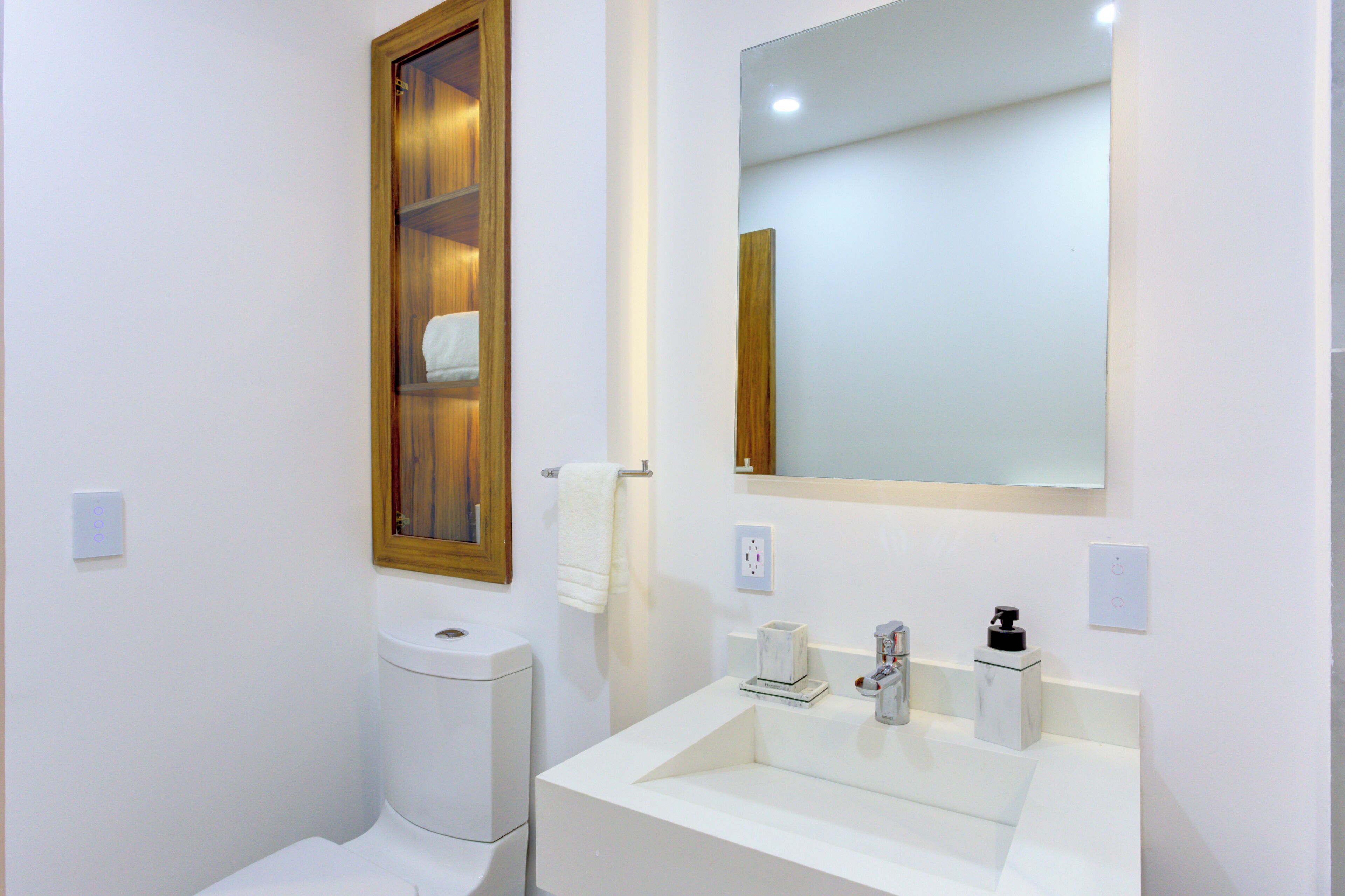 Pamper yourself at a contemporary floating vanity sink, complete with a wide mirror and a built-in wooden shelving nook for fresh towels.