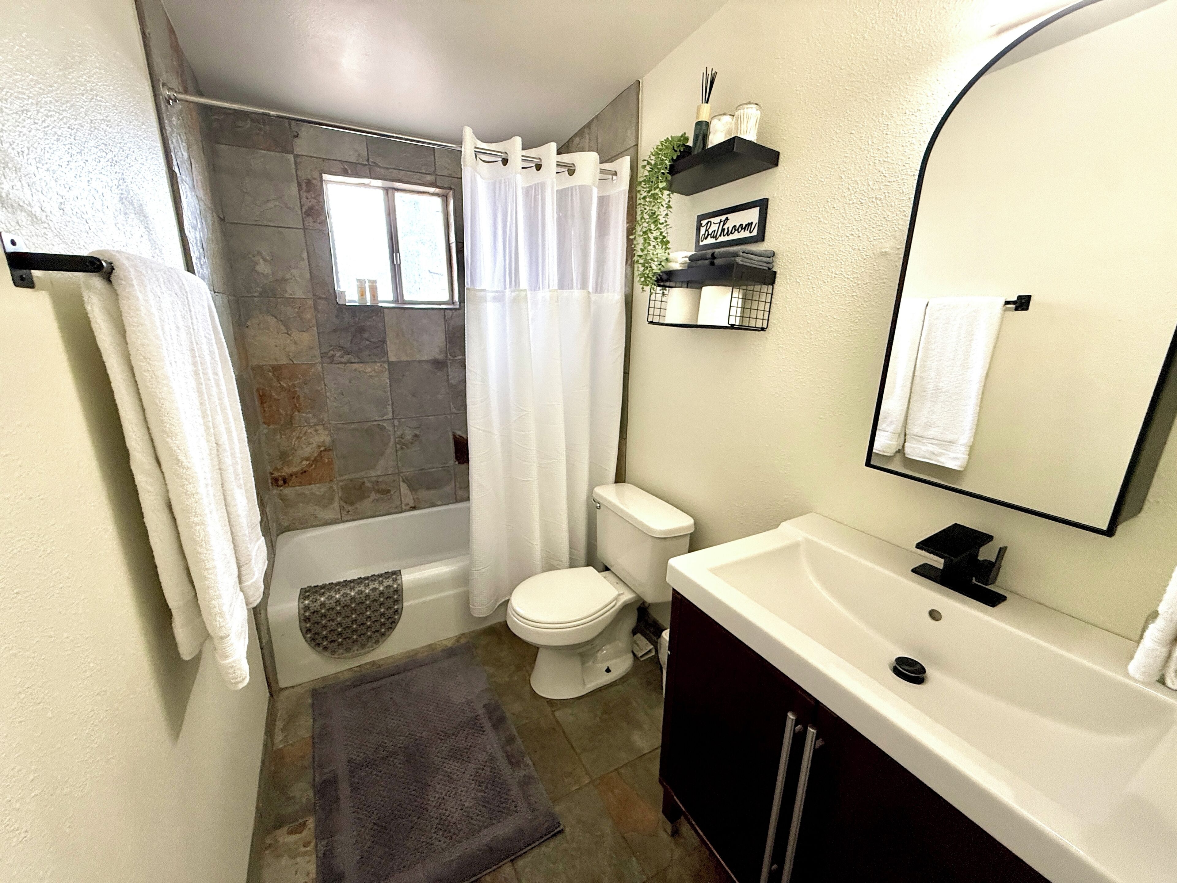 Une salle de bain équipée d’une douche, de toilettes, d’un lavabo et d’un miroir.