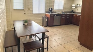 A compact kitchen with a dining area, featuring a dishwasher, a coffee maker, and a small trash bin. - Bright and Cozy Tucson Condo - Ideal for families, couples and friends (Tucson)