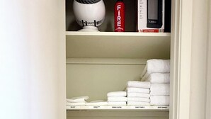 A closet with shelves containing folded towels, a fire extinguisher, a hairdryer, and a Lasko hairdryer. - Bright and Cozy Tucson Condo - Ideal for families, couples and friends (Tucson)