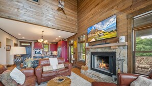 A spacious living room with leather sofas, a fireplace, and a large painting on the wall. - Mountaintop Lodge with Views (Boone)