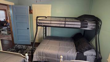 A room with a bunk bed, a ceiling fan, and a door leading to another room.
