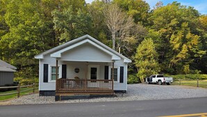 A single-story mobile home with a porch, located next to a gravel driveway and a road with double yellow lines. - Rowdy Ridge Yee Yee (Northfork)