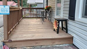 A wooden porch with a railing, a table with chairs, and a potted plant. - Rowdy Ridge Yee Yee (Northfork)