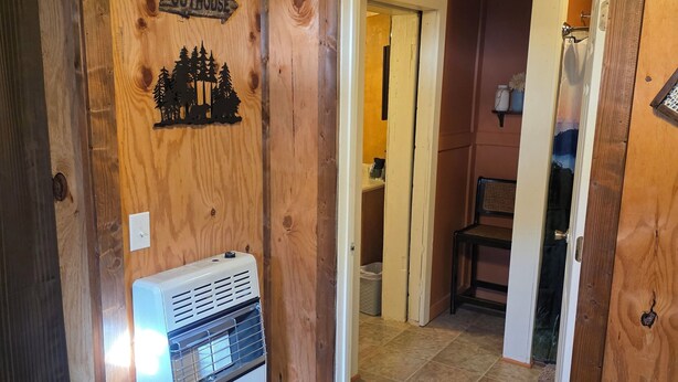 A wooden interior with a sign reading "Outhouse" and a heater. - Rowdy Ridge Yee Yee (Northfork)