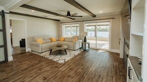 A spacious living room with a sectional sofa, wooden flooring, and a ceiling fan. - The Hidden Gem a Waterfront Property (Arcadia)