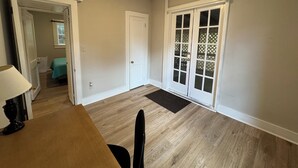 A spacious room with a wooden floor, a dining table, and a door leading to a balcony. - Located near UGA, Normaltown, & Downtown Athens. Charming 2-bed cottage w/ AC. (Athens)