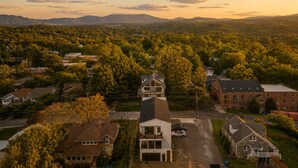 Un quartier résidentiel avec des maisons, un immeuble à deux étages doté d’un balcon, et une chaîne de montagnes en arrière-plan.