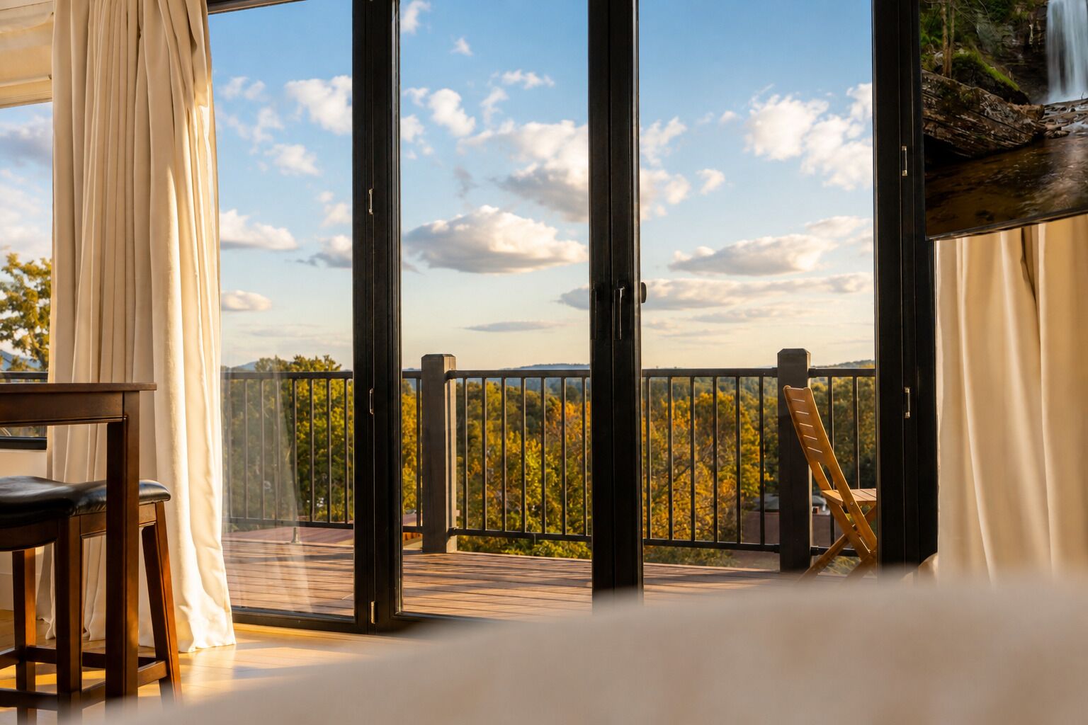Una habitación con vistas a un bosque y una cascada, visibles a través de amplios ventanales.
