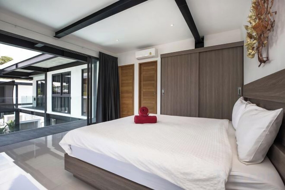 A modern bedroom with a large bed, a sliding door, and a view through a glass door.