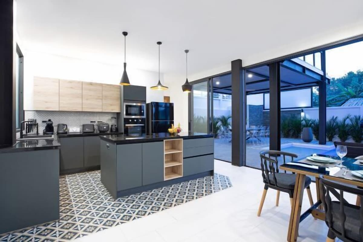 A modern kitchen with a central island, built-in appliances, and pendant lighting.