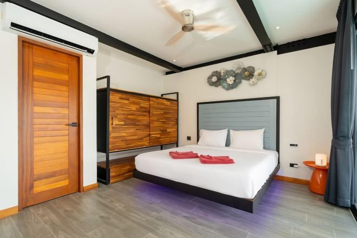 A hotel room with a bed, a ceiling fan, a wardrobe, and a nightstand.