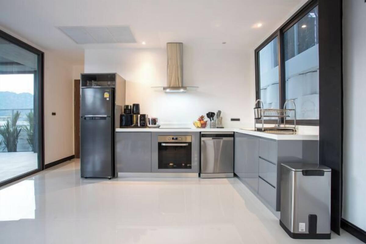 A modern kitchen with a refrigerator, oven, dishwasher, and a large window.