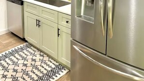 Uma cozinha moderna com eletrodomésticos de aço inoxidável, um dispensador de água embutido e armários verde-claros.