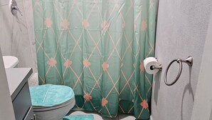 Ein Badezimmer mit Toilette, Waschbecken, Duschvorhang und einem Handtuch auf dem Boden.