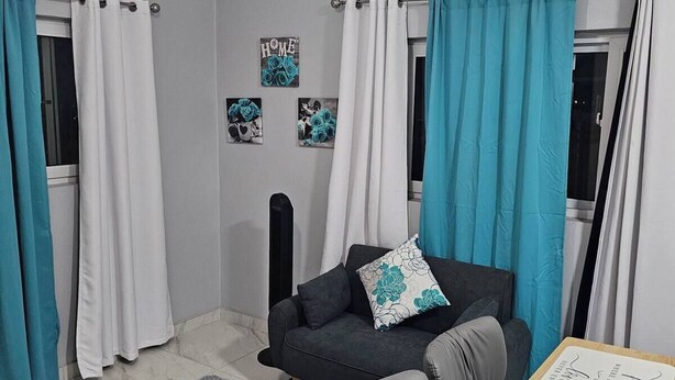 Ein modernes Wohnzimmer mit einem schwarzen Sofa, einem grauen Teppich und einem Holztisch mit Unterlage.