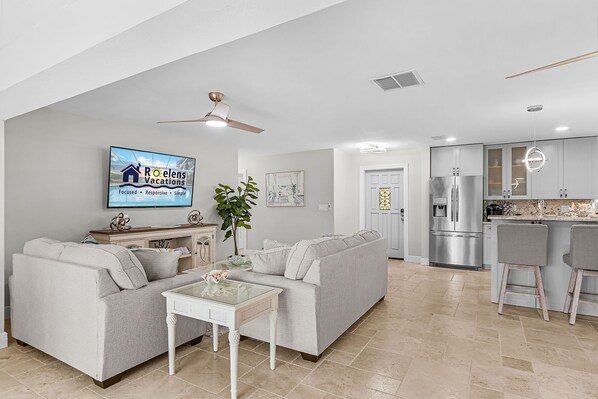 A modern living room with a grey sofa, a coffee table, and a television displaying a vacation ad.