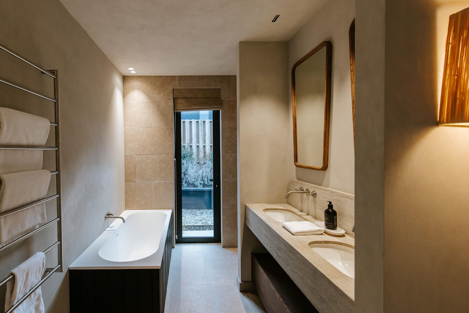 Un baño moderno con bañera, dos lavamanos y un espejo grande.