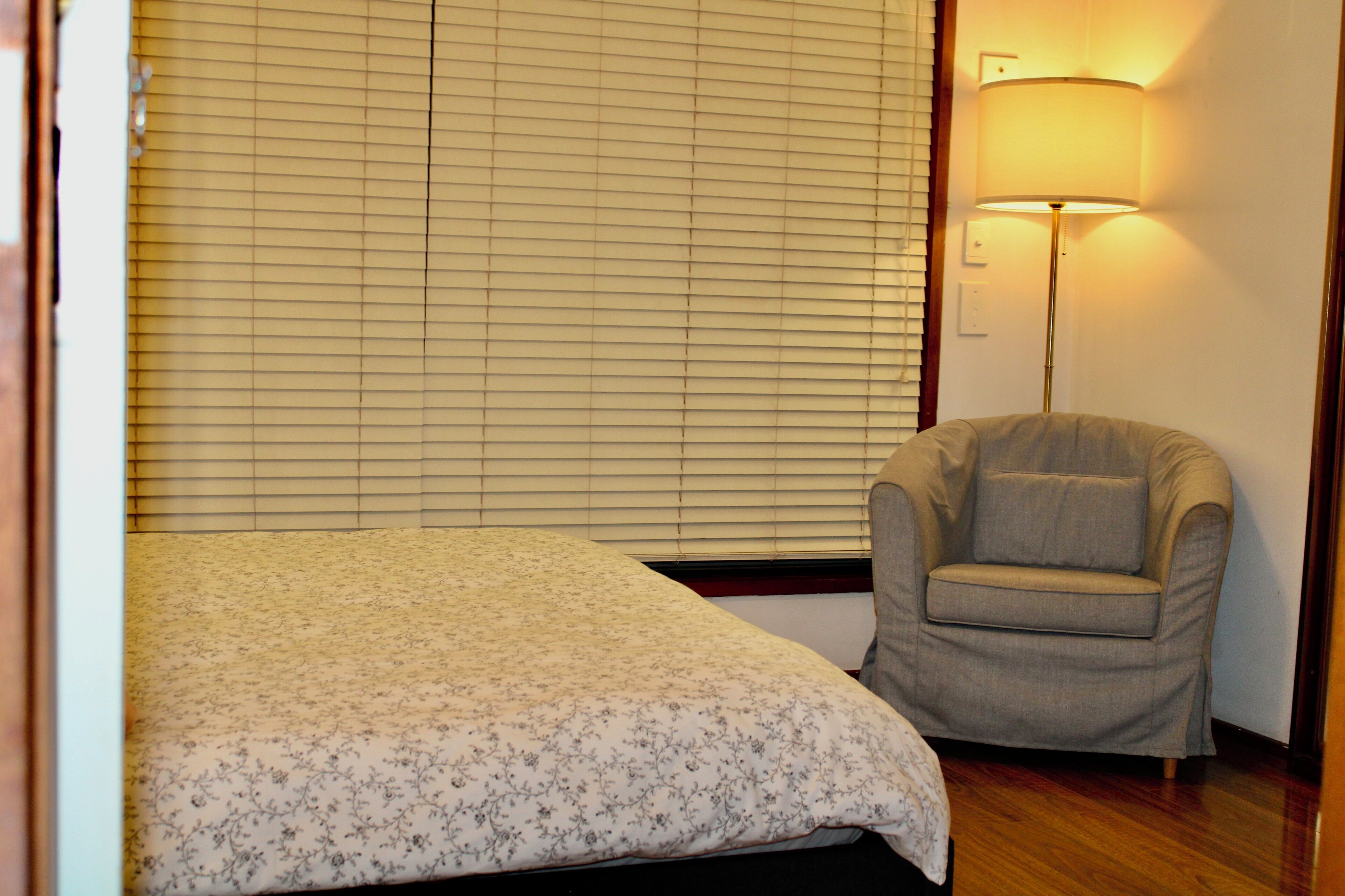 A bedroom with a bed, a chair, and a lamp.