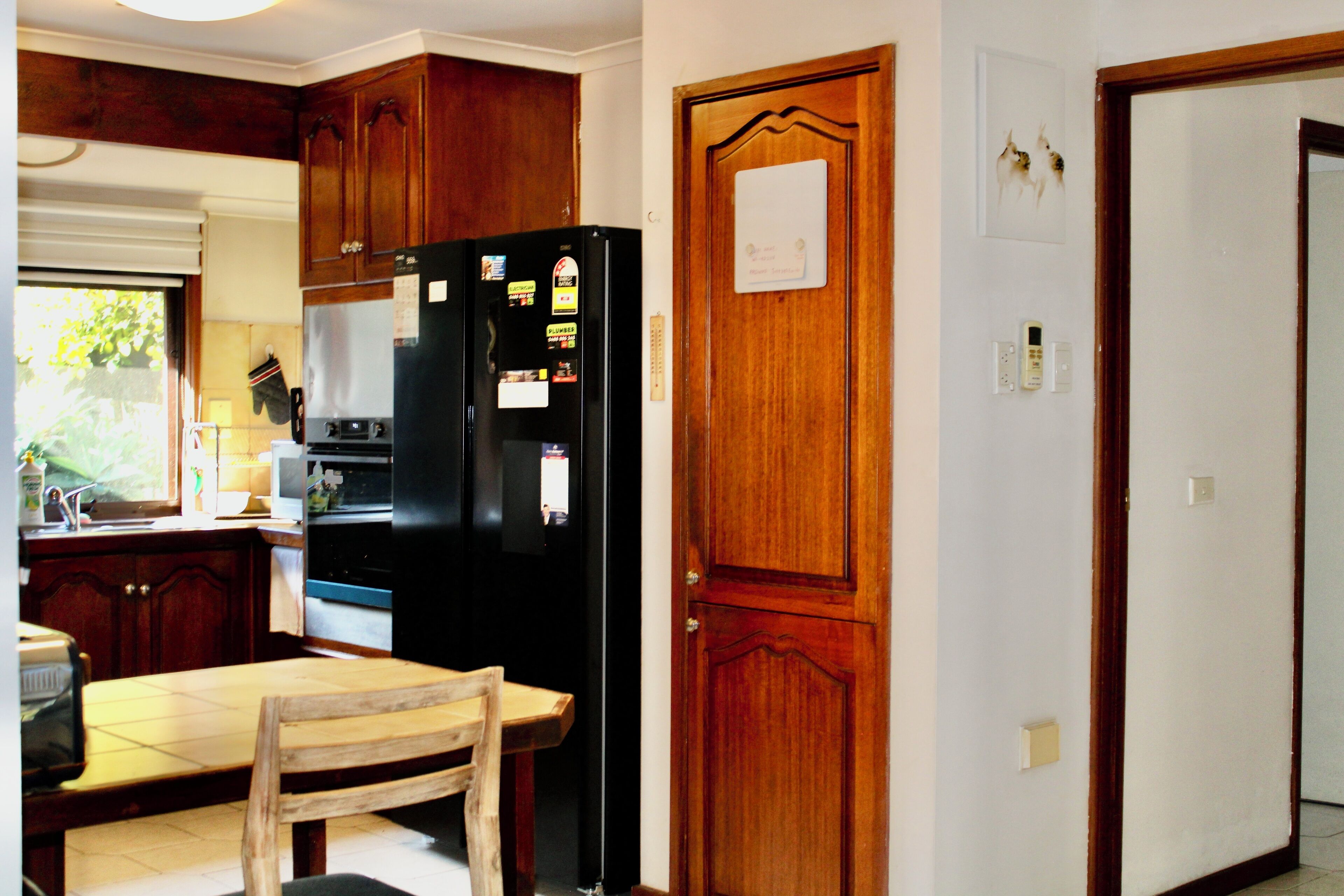 Una cocina con armarios de madera, un refrigerador negro y un comedor de madera con sillas.
