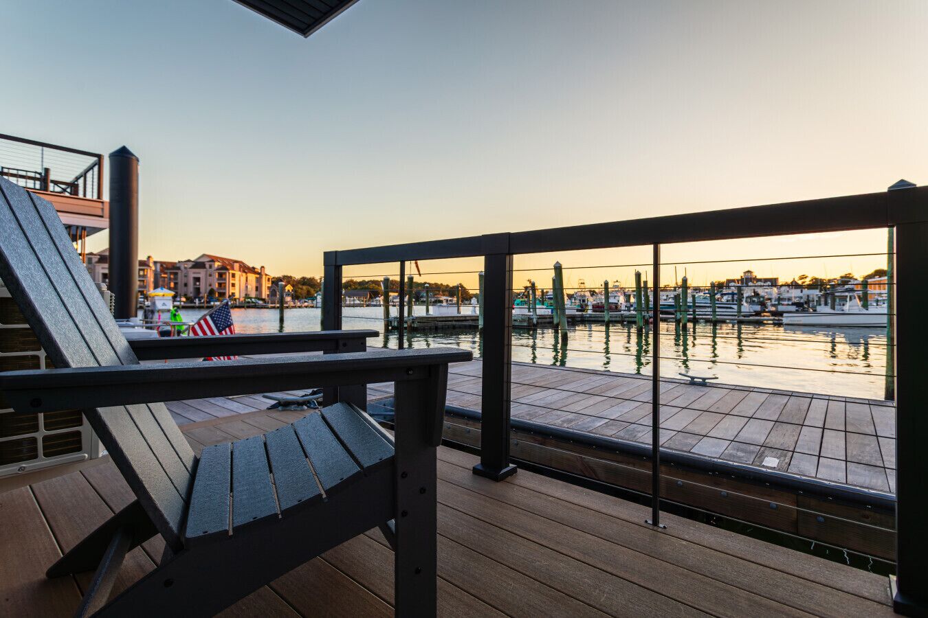 A wooden deck with a metal railing overlooking a marina with boats.
