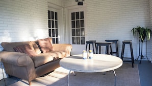 A cozy living room with a brown leather sofa, a round coffee table, and a white brick wall.