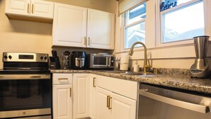 A modern kitchen with white cabinets, stainless steel appliances, and a granite countertop.