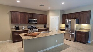 A modern kitchen with dark wooden cabinets, stainless steel appliances, and a granite countertop.