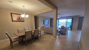 A spacious living area with a dining table and chairs, a television, and a view of the outdoors.