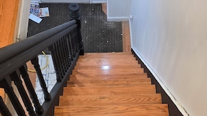 A wooden staircase with a black railing leading to a door with a decorative glass panel. - Stunning 5-bedroom house with AC / Heat in charming Poughkeepsie NY (Poughkeepsie)