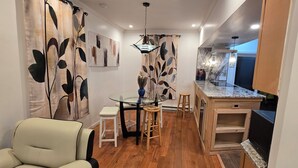 A modern kitchen with a marble countertop, wooden cabinets, and a dining area with a glass table and stools. - Stunning 5-bedroom house with AC / Heat in charming Poughkeepsie NY (Poughkeepsie)