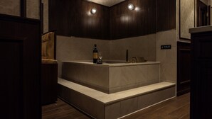 Ein modernes Badezimmer mit einer großen Badewanne, einem Holzstuhl und einer Weinflasche auf der Ablagefläche.