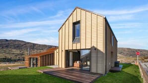 A modern house with a large open porch, a garage, and a stop sign in the background. - The Pisa (Cardrona)