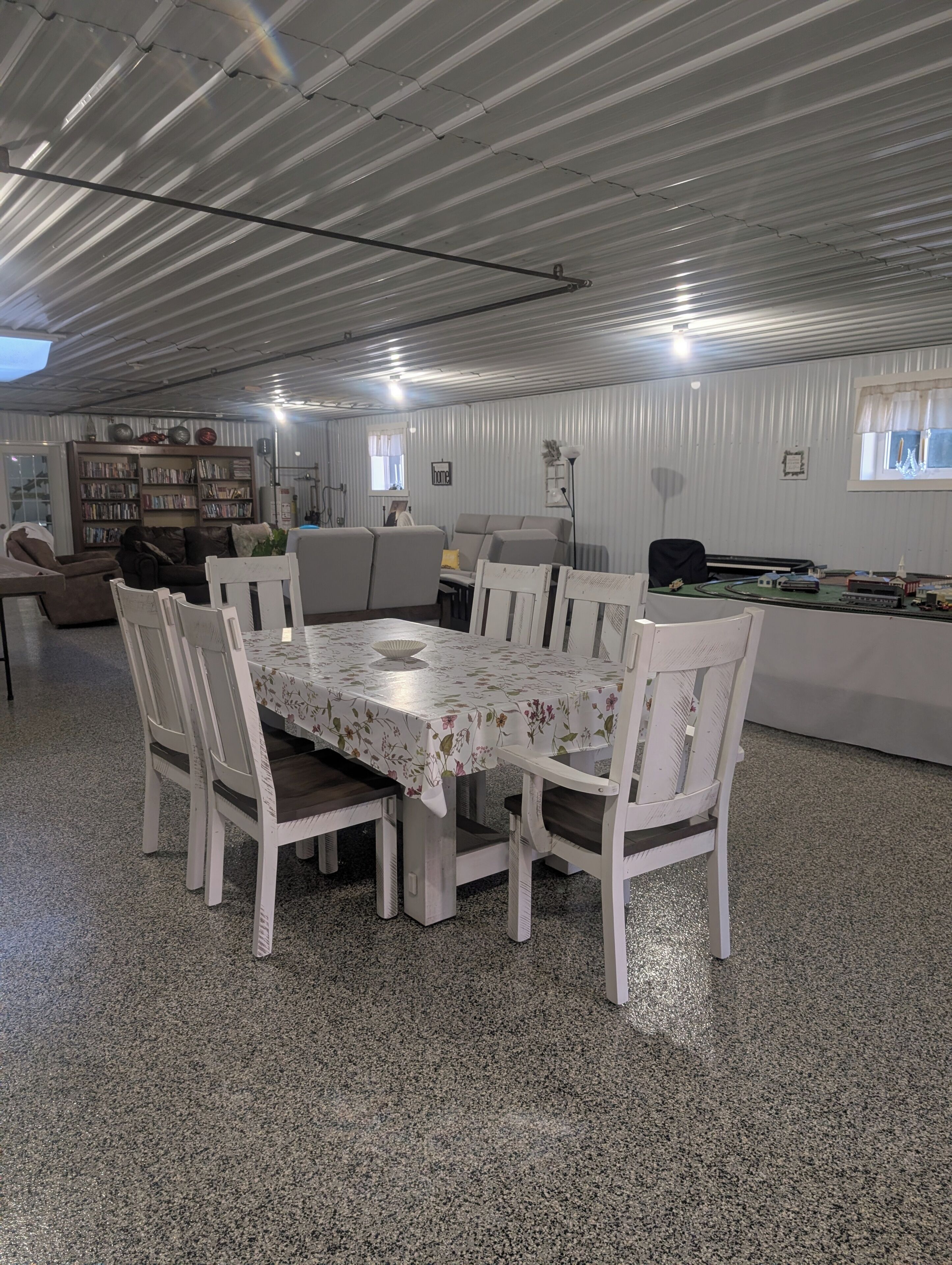 Un comedor con una mesa y sillas, una estantería y un sofá.