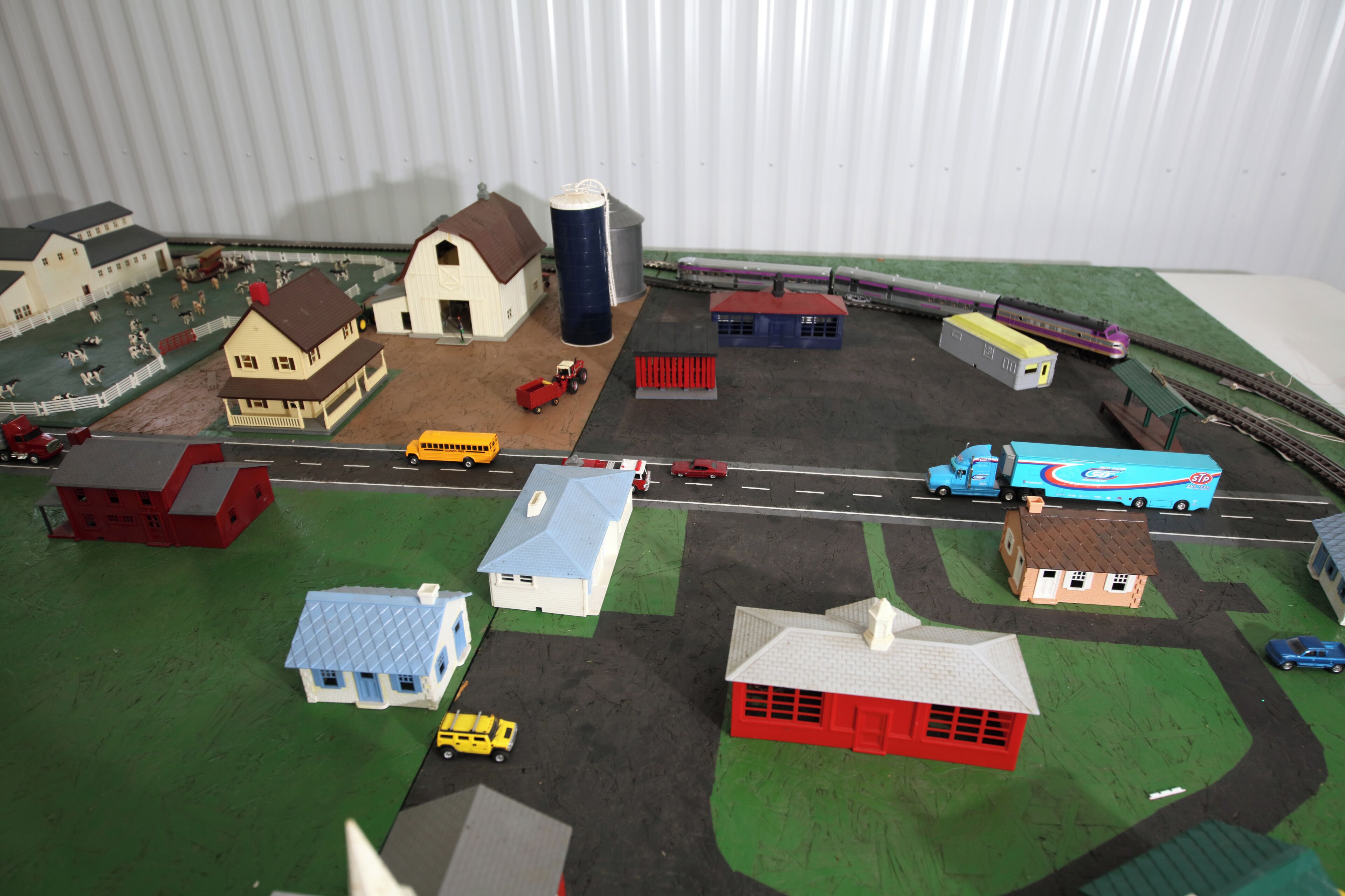 A model train layout with buildings, vehicles, and tracks.