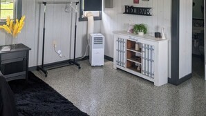 A room with a white ceiling, a black floor, a white cabinet with a plant, a black chair, and a window with a view.