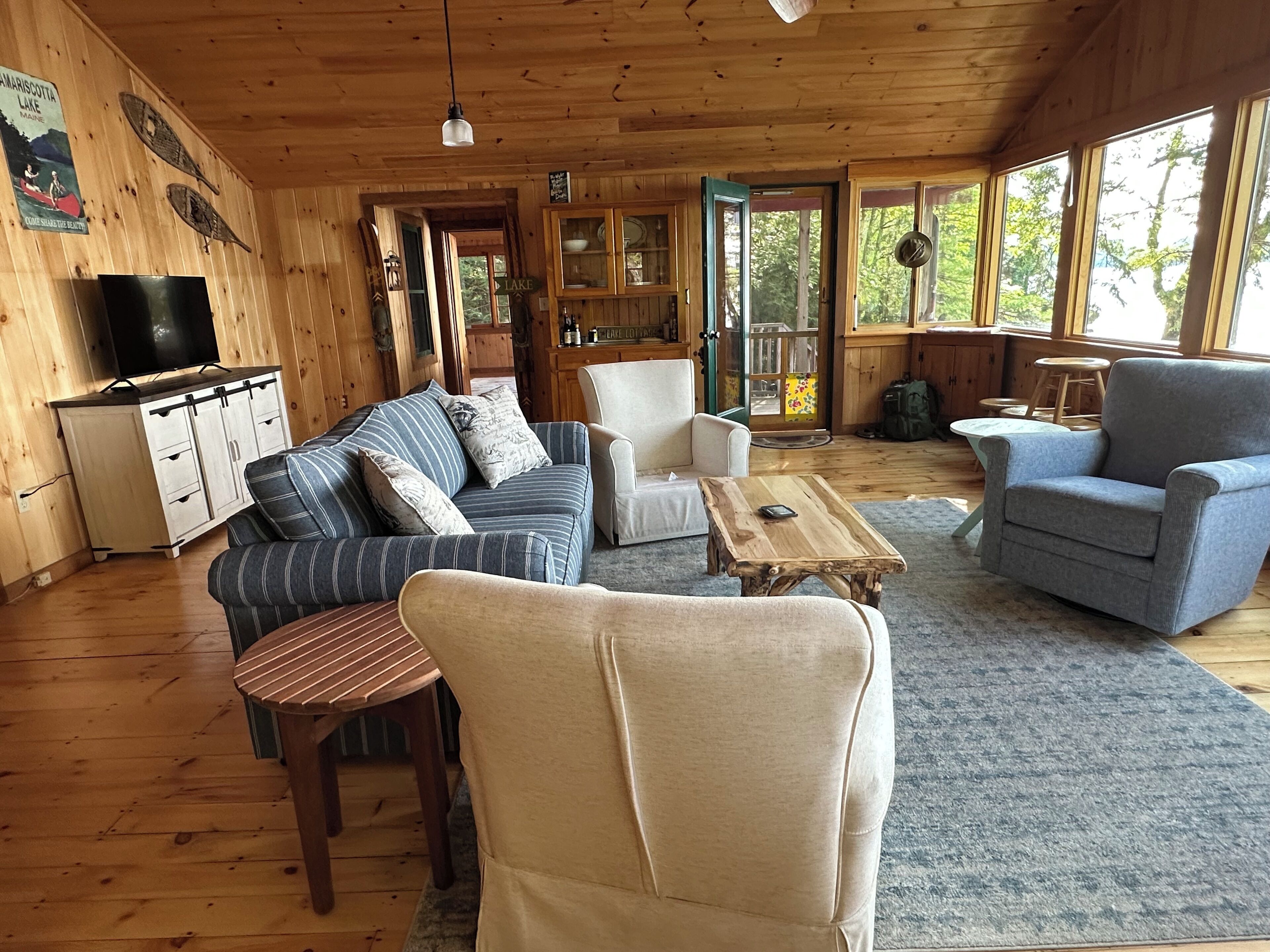 L’intérieur d’un chalet accueillant, avec des murs en bois, un téléviseur, un canapé, un fauteuil et une table.