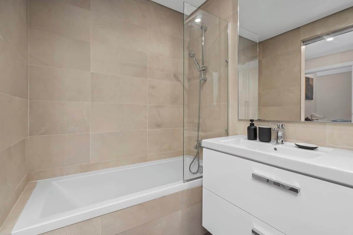 Une salle de bain moderne avec une douche à parois de verre, une baignoire blanche et un meuble-lavabo avec un miroir.