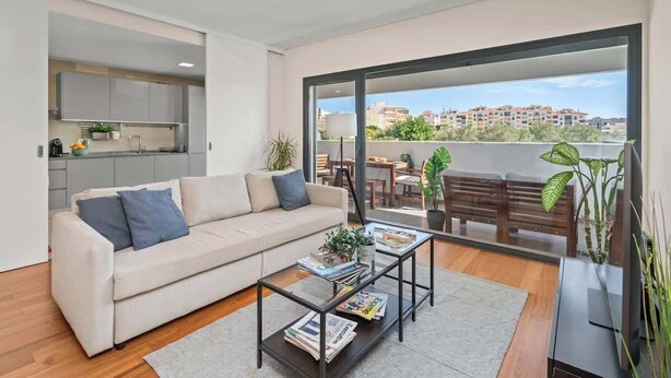 Un appartement moderne comprenant un salon, une kitchenette et un balcon avec vue sur la ville.