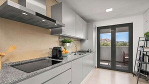 Une cuisine moderne dotée d’un plan de travail en granit, d’appareils électroménagers en acier inoxydable et offrant une vue à travers une porte vitrée.
